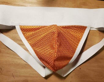 Pode incluir: Um suporte atlético laranja e branco com uma cintura elástica larga e alças. A taça laranja tem um design texturizado e respirável. Projetado para atividades atléticas.
