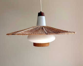 May include: A mid-century modern pendant light with a white and brown color scheme. The light fixture features a white glass shade, a woven rattan base, and a conical light blue top. The shade is surrounded by a woven, brown, fringed material.