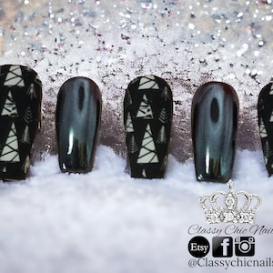 May include: Five black and white Christmas tree patterned press-on nails with a black and silver glitter accent nail. The nails are displayed on a white surface with a crown and the text "Classy Chic Nails" and social media icons.