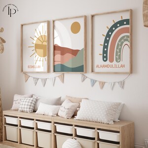Puede incluir: Tres impresiones enmarcadas con un diseño minimalista. Las impresiones presentan un sol, una cordillera y un arcoíris. Las impresiones están colgadas en una pared blanca sobre un banco de madera con contenedores de almacenamiento. Las impresiones tienen las palabras "Bismillah" y "Alhamdulillah" escritas en ellas.