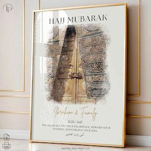Puede incluir: Un estampado enmarcado con borde dorado presenta el texto "HAJJ MUBARAK" sobre una imagen de una puerta dorada con escritura &aacute;rabe. Debajo, el texto "Ibrahim & Family" y un mensaje de buenos deseos. Arte mural de tem&aacute;tica religiosa.