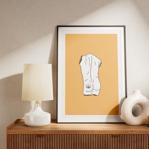Peut inclure: Une impression encadr&eacute;e avec un dessin au trait minimaliste d'une figure nue avec un &oelig;il au dos. Le fond est de couleur orange clair.