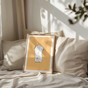 Peut inclure: Une impression encadr&eacute;e avec un fond jaune et un dessin au trait blanc d'une figure humaine avec un &oelig;il sur le dos.