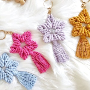 May include: A collection of star-shaped keychains in various colors, including blue, pink, purple, and yellow, with gold key rings and matching tassels. A wooden comb and a star made of wooden beads are also visible.