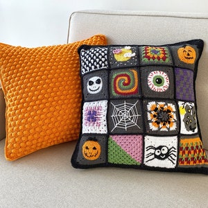 May include: Two decorative throw pillows, one orange and one black with a patchwork design featuring various Halloween-themed motifs, including pumpkins, spiders, and a skull. The pillows are on a light beige couch.