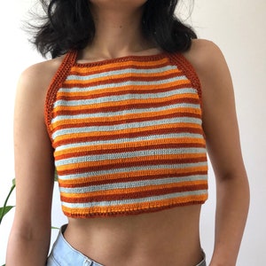 May include: A striped crochet halter top with orange and blue stripes. The top is cropped and has a halter neck style.