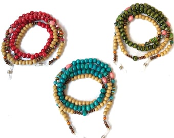 May include: Three pairs of colorful beaded eyeglass chains. The chains are made of wooden beads in various colors, including red, green, blue, and brown. The chains are strung together with small metal beads and have metal clasps at the ends.