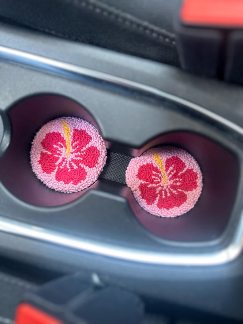 May include: Two pink and red car cup holders with a hibiscus flower design.