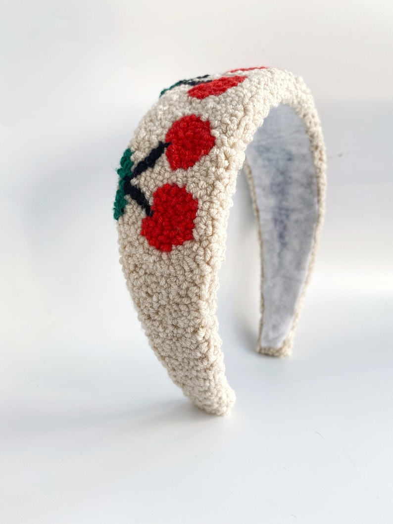 Pu&ograve; includere: Un cerchietto color crema con ciliegie ricamate in rosso e verde. Il cerchietto &egrave; realizzato in un materiale morbido e soffice.