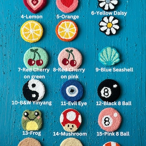 May include: A collection of 18 colorful, hand-crafted, round rug hookings. The designs include hearts, lemons, cherries, seashells, yin-yang, an evil eye, a frog, a mushroom, and an 8-ball.
