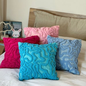 May include: Four decorative throw pillows with a unique, abstract, brain-like pattern. The pillows are in shades of pink, blue, turquoise, and red.