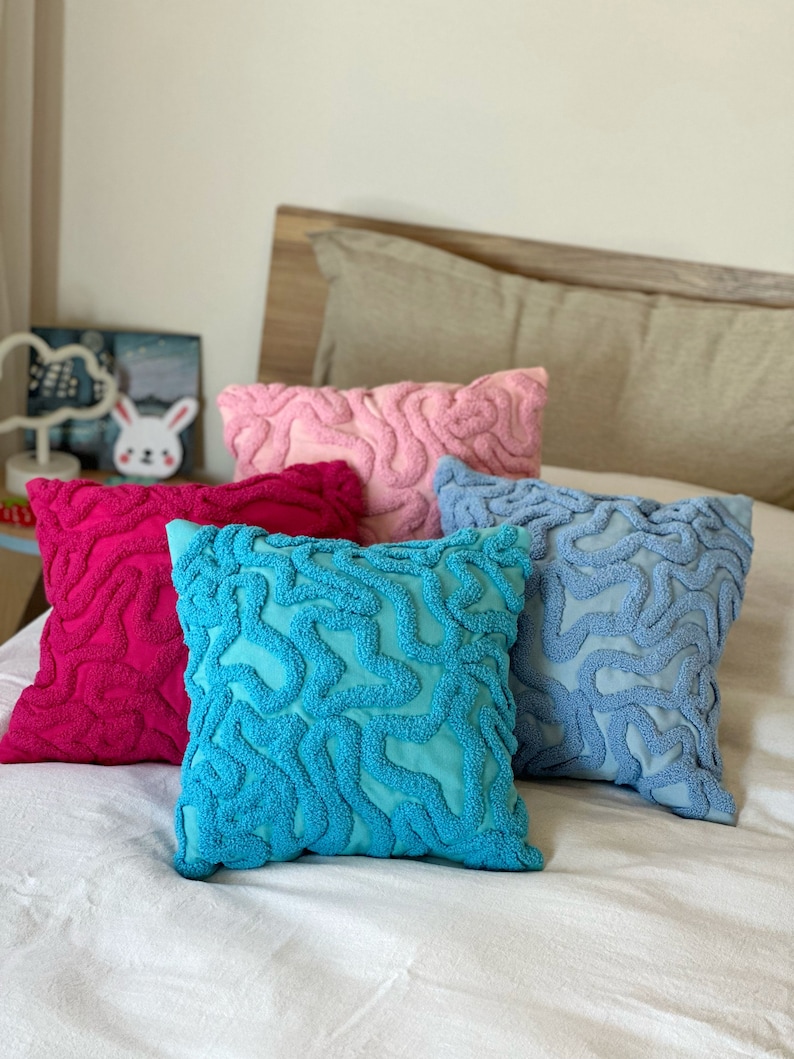 May include: Four decorative throw pillows with a unique, abstract, brain-like pattern. The pillows are in shades of pink, blue, turquoise, and red.