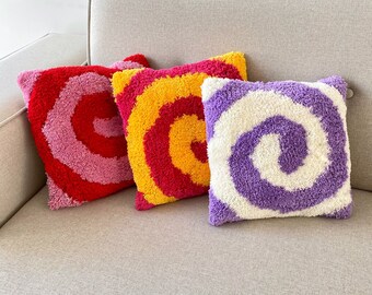 May include: Three decorative throw pillows with a swirling pattern. The pillows are pink and red, yellow and red, and purple and white.