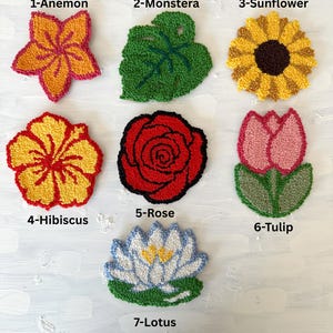 May include: A collection of seven colorful, handmade floral designs. The designs include an Anemone, Monstera leaf, Sunflower, Hibiscus, Rose, Tulip, and Lotus. Each design is labeled with a number and the flower's name.