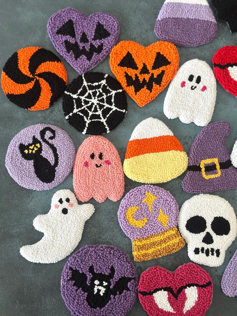 May include: A collection of Halloween-themed, textured, decorative items. Includes a variety of shapes such as pumpkins, ghosts, bats, and skulls, in colors like orange, purple, black, and white. The items appear to be handmade and are arranged on a flat surface.