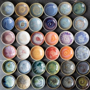 May include: A white ceramic mug with a black handle and the text "But First, Coffee" in a handwritten style. The mug is likely for hot beverages and has a glossy finish.