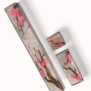 Peut inclure: Un ensemble de trois touches de clavier en r&eacute;sine avec un fond blanc, une branche d'arbre brune et des fleurs de cerisier roses. Les touches sont con&ccedil;ues pour un clavier m&eacute;canique.