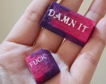 Tasti artigianali con scritta "imprecazione", tema galassia viola e rosa.