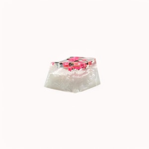 Peut inclure: Un capuchon de touche en r&eacute;sine transparente avec des fleurs roses incrust&eacute;es &agrave; l'int&eacute;rieur. Le capuchon de touche est blanc et a une surface textur&eacute;e.