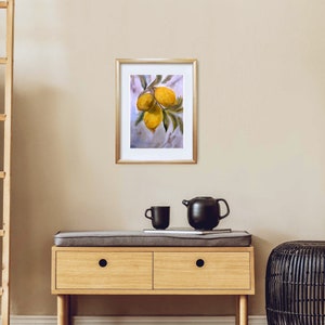 May include: A framed watercolor painting of three yellow lemons hanging from a branch with green leaves. The background is a light blue watercolor wash.