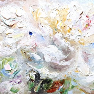 May include: Close-up of an abstract oil painting featuring a cluster of white flowers with textured brushstrokes. The artwork has accents of yellow, pink, green, and blue, creating a vibrant and detailed floral composition. The painting is on a neutral background.