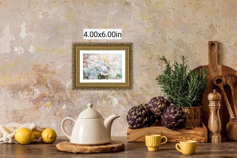 May include: A still life featuring a framed 4.00x6.00in painting, a white teapot, lemons, artichokes, and rosemary. The painting has a gold frame. Two yellow cups and a wooden cutting board are also present.