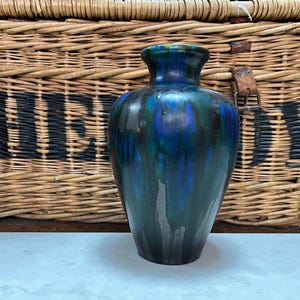 May include: A dark green ceramic vase with blue and silver streaks. The vase has a rounded body and a narrow neck.