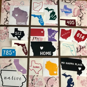 May include: A collection of vinyl stickers featuring various state outlines with the words "home", "native", and area codes. The stickers are on a pink and white floral patterned background.