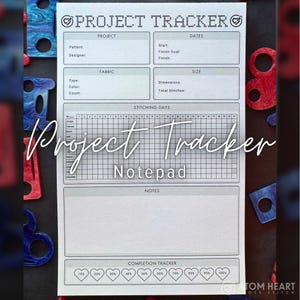 May include: A white Project Tracker Notepad with sections for project details, dates, fabric, size, stitching days, notes, and completion tracker. The notepad has a grid for tracking progress and is surrounded by colorful craft supplies.