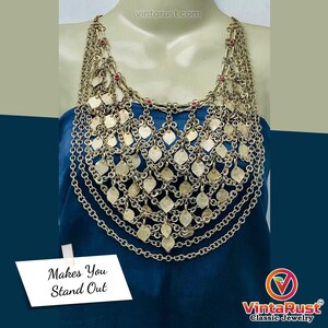 Può includere: Una collana vintage color argento con più strati di catene e ciondoli a forma di foglia. La collana ha piccoli accenti rossi e verdi ed è esposta su un manichino. Il testo "Makes You Stand Out" è visibile.