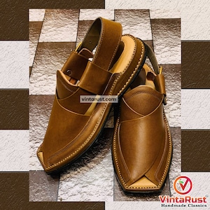 K&ouml;nnte beinhalten: Ein Paar braune Ledersandalen mit spitzer Zehenpartie und einem Riemen &uuml;ber dem Fu&szlig;r&uuml;cken. Die Sandalen haben ein gen&auml;htes Design und eine schwarze Sohle.