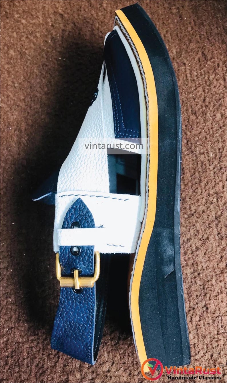 Pu&ograve; includere: Sandali in pelle bianca e blu con bordino giallo e chiusura a fibbia. I sandali hanno una suola nera spessa. I sandali sono fatti a mano e sono in stile vintage.