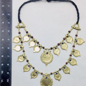 May include: A gold necklace with a double strand of brown beads and gold coin-shaped pendants. The pendants have blue stones in the centre. The necklace is approximately 18 inches long.