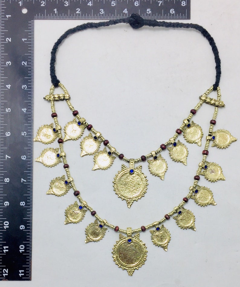 May include: A gold necklace with a double strand of brown beads and gold coin-shaped pendants. The pendants have blue stones in the centre. The necklace is approximately 18 inches long.