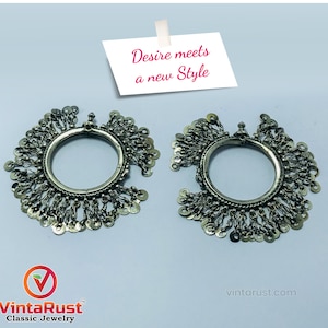 Può includere: Un paio di orecchini d'argento con un design circolare e catene pendenti con piccoli dischi rotondi. Gli orecchini sono su uno sfondo bianco con un biglietto che dice "Desire meets a new Style".