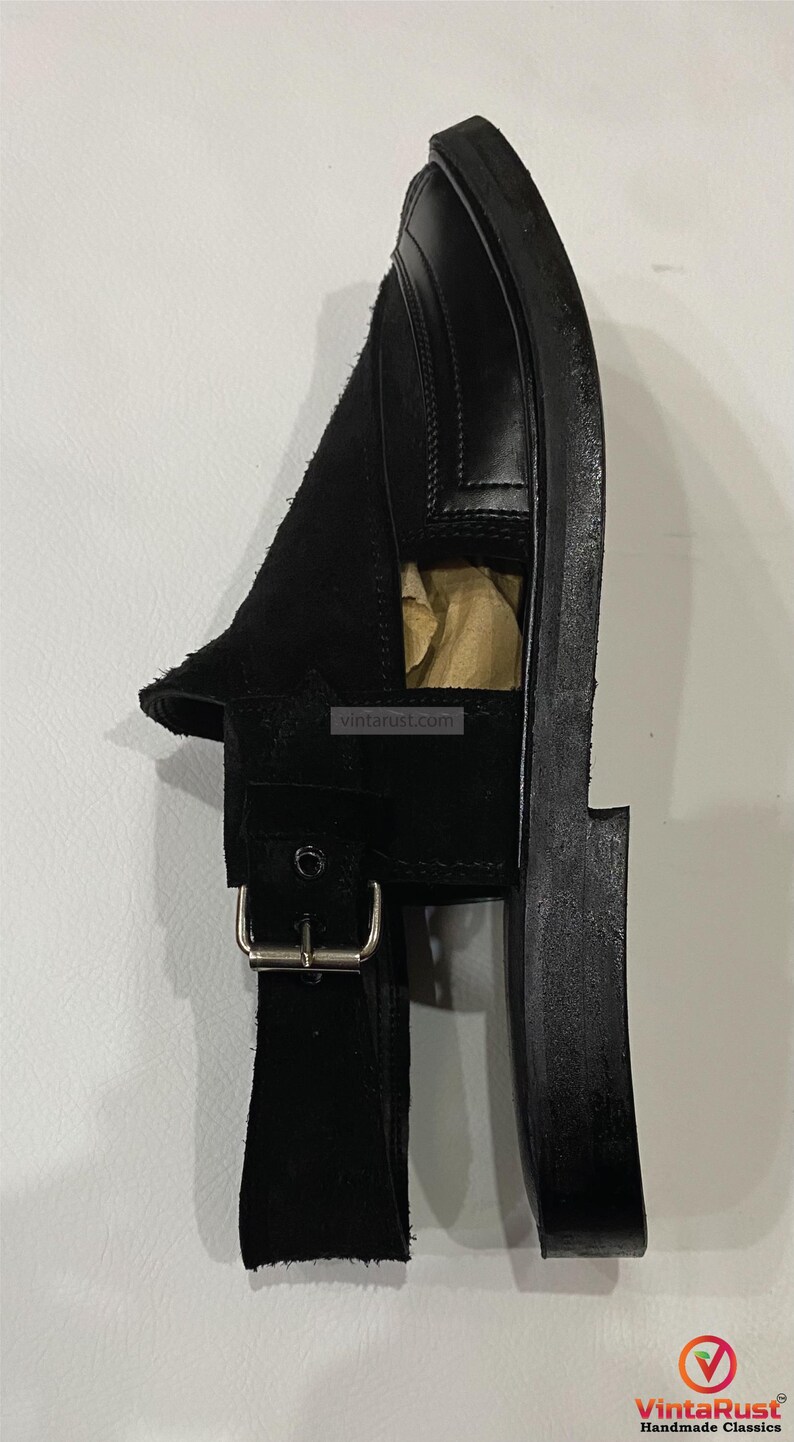 May include: Black leather sandal with a suede vamp and a buckle closure. The sandal has a thick sole and a minimalist design. The image also shows the website vintarust.com.