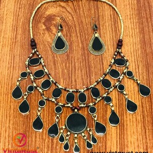 Pode incluir: Um colar de ouro com contas pretas e marrons e um grande pingente preto. O colar &eacute; acompanhado por um par de brincos combinando com pedras pretas em forma de l&aacute;grima.