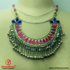 Può includere: Una collana d'argento con perline di vetro rosa e blu e una frangia di campanelle d'argento. La collana è su un manichino.