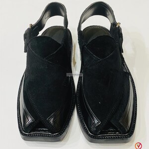 May include: A pair of black leather Peshawari sandals. The sandals feature a square toe design with a glossy finish on the toe cap and a suede upper. The sandals have an adjustable strap and buckle closure.