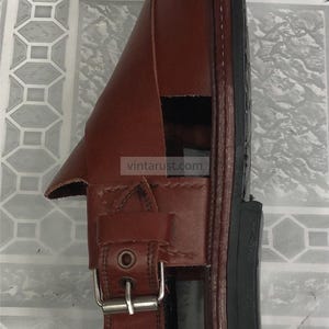 Puede incluir: Sandalia de cuero marr&oacute;n con cierre de hebilla y suela negra. La sandalia tiene un dise&ntilde;o cl&aacute;sico y es adecuada para uso casual. La imagen incluye el texto "vintarust.com".
