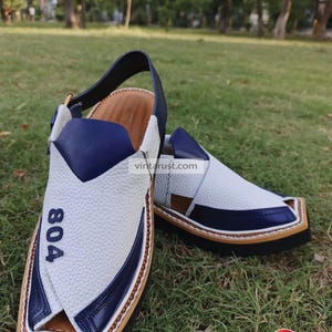 Pu&ograve; includere: Sandali in pelle bianca con dettagli blu e suola marrone. I sandali hanno una punta a punta e un cinturino che va intorno alla caviglia. I sandali hanno il numero "804" scritto su di loro.