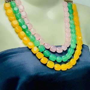 May include: A three-strand necklace with yellow, green, and pink square beads.
