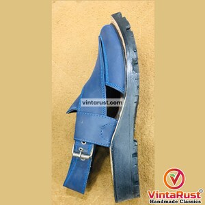 May include: A blue leather sandal with a buckle closure and a thick black sole. The sandal features a strap across the top and a strap around the ankle. The text "vintarust.com" is visible on the sandal.