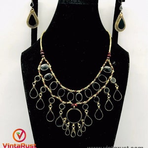 Pode incluir: Um colar de ouro com contas de vidro preto e transparente e pingentes em forma de l&aacute;grima. O colar &eacute; combinado com brincos correspondentes. O colar est&aacute; em um expositor preto.  www.vintaRust.com