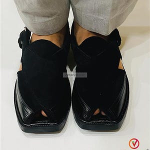 May include: A pair of black leather Peshawari sandals. The sandals have a distinctive open-toe design with a strap and buckle closure. The upper part of the sandal is made of a combination of smooth and textured leather.