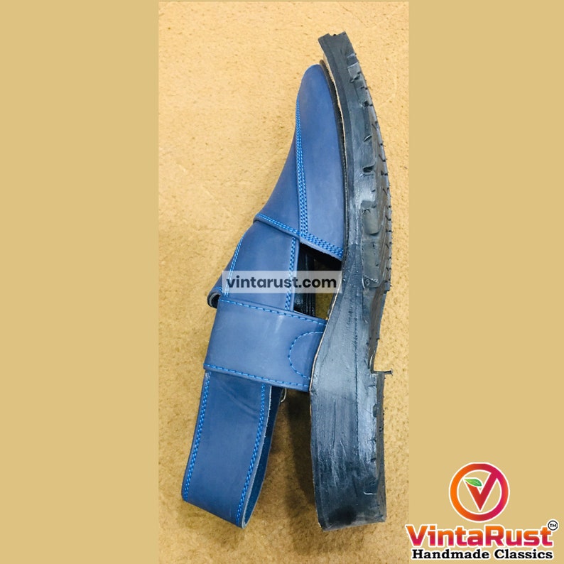 May include: Blue leather sandal with a strap and buckle closure. The sole is black and textured. The sandal has a classic design and is suitable for casual wear. The image includes the text "vintarust.com".