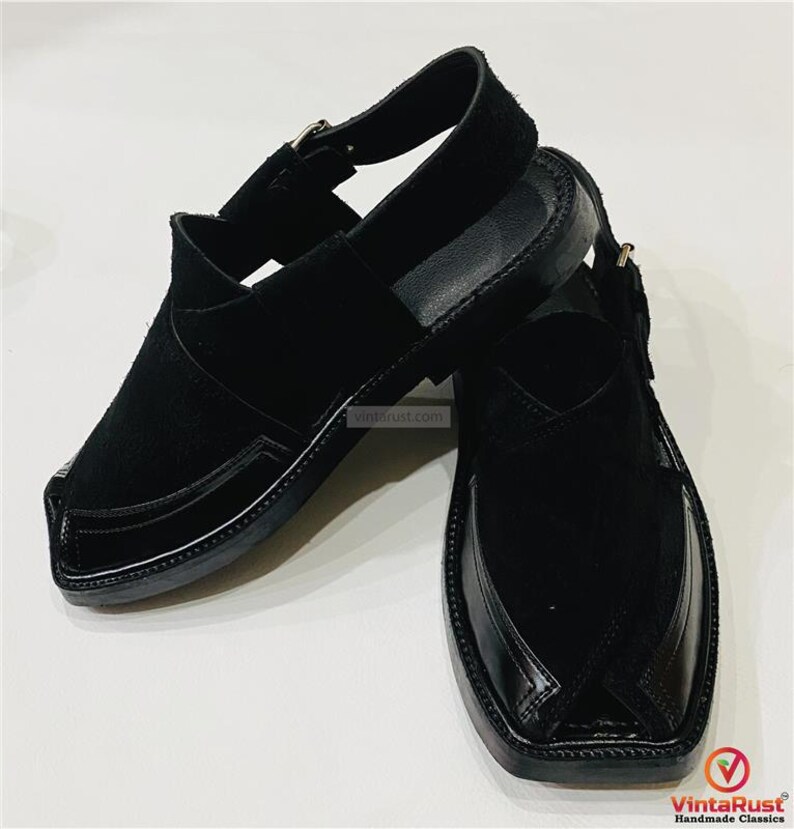 May include: A pair of black leather sandals with a closed-toe design. The sandals feature a strap that goes around the ankle and a buckle closure. The upper part of the sandal is made of suede, and the sole is made of leather.