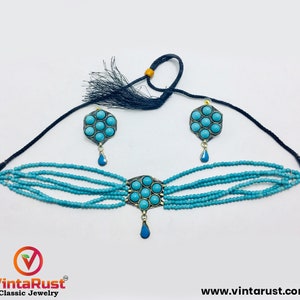 May include: A turquoise blue choker necklace with a multi-strand design and a pendant featuring a turquoise stone cluster. Matching earrings with turquoise stone clusters are also included.