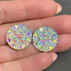 May include: Two iridescent round rhinestones with a faceted design. The rhinestones are approximately 1 inch in diameter.