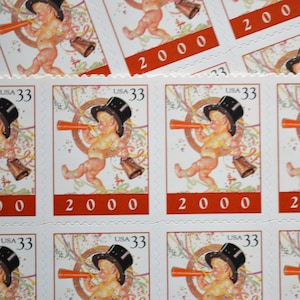 May include: Sheet of commemorative stamps featuring a cherubic figure in a top hat blowing a horn, with a bell and confetti. The stamps are marked "USA 33" and "2000" in red.